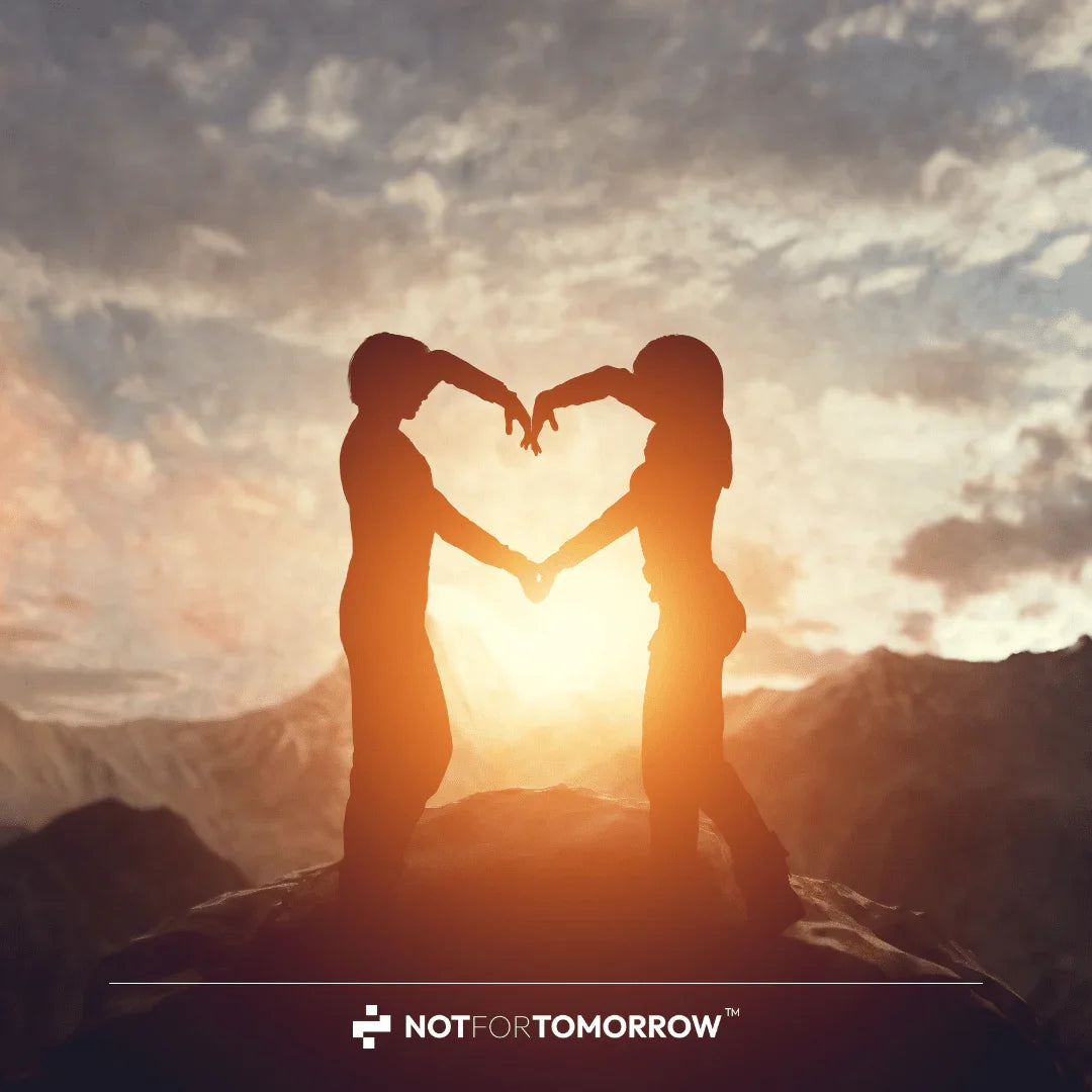 Silhouettes of two people forming a heart shape at sunset in the mountains, symbolizing health and vitality.