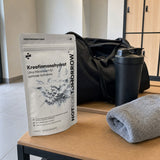 NOTFORTOMORROW Kreatinmonohydrat 500 g pose på en omklædningsbænk ved siden af en sportstaske, en shaker og et håndklæde