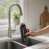 NOTFORTOMORROW MAGBOTL black water bottle at kitchen sink with modern tap, hand fills bottle with water
