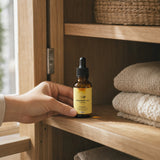 Hand zet het amberkleurige NOTFORTOMORROW Vitamine D3 + K2 flesje op een plank in een houten kast